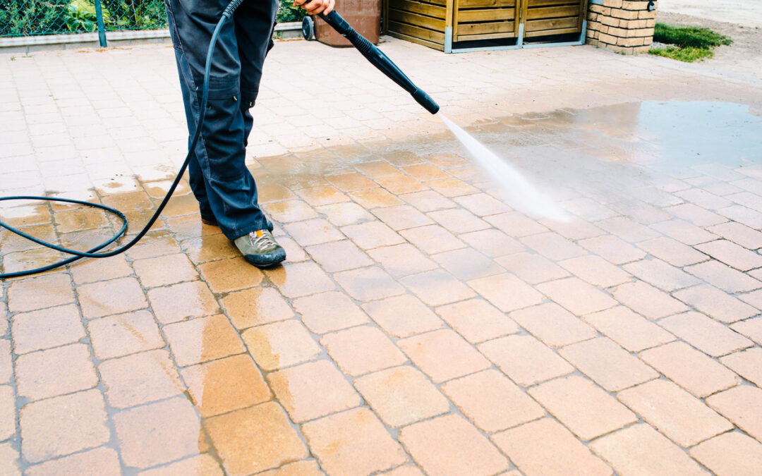 Outdoor floor cleaning with high pressure water jet - cleaning concrete block floor on terrace, patio pressure washing